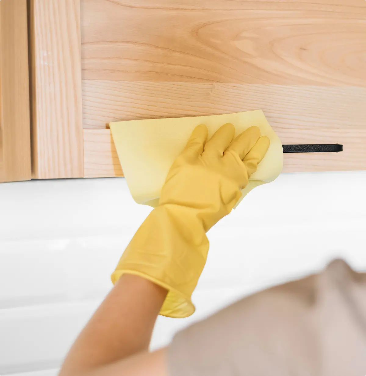Image of a cleaner wiping down a cabinet.